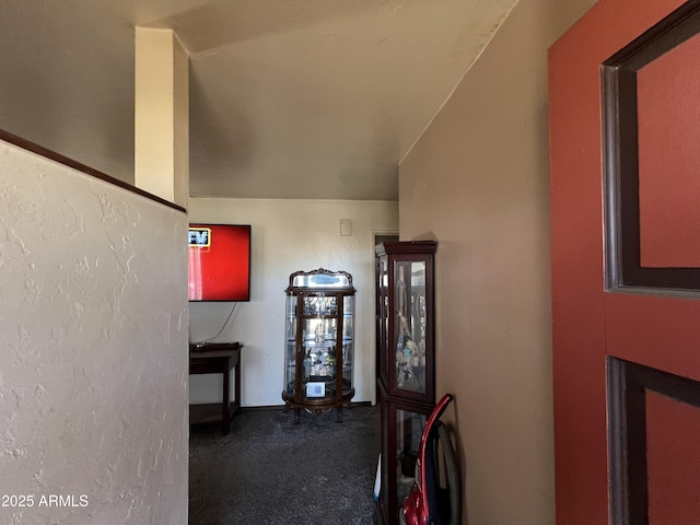 hallway featuring dark carpet and vaulted ceiling