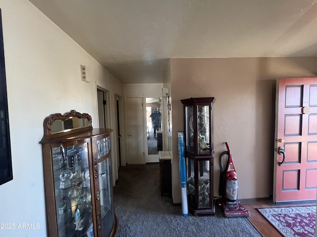 foyer featuring dark colored carpet