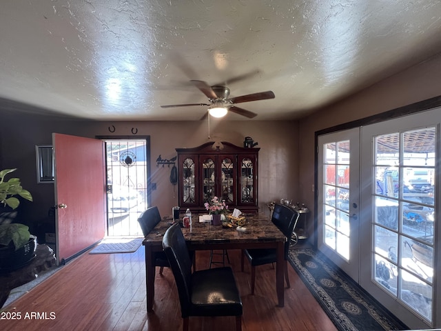 dining space with hardwood / wood-style flooring, ceiling fan, a textured ceiling, and french doors