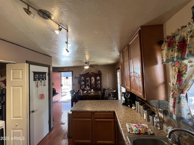 kitchen with kitchen peninsula, a textured ceiling, ceiling fan, sink, and dark hardwood / wood-style floors