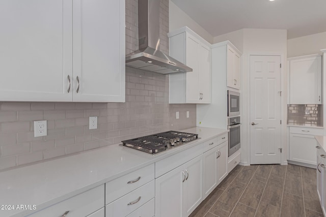 kitchen with wall chimney range hood, white cabinets, backsplash, dark hardwood / wood-style floors, and stainless steel appliances