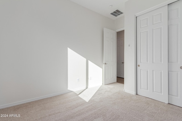 unfurnished bedroom featuring light carpet and a closet