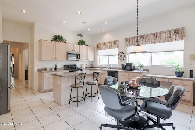 kitchen featuring stainless steel appliances, a sink, a breakfast bar, a center island, and light tile patterned floors