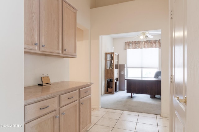 kitchen with light brown cabinets, light carpet, ceiling fan, light countertops, and light tile patterned floors