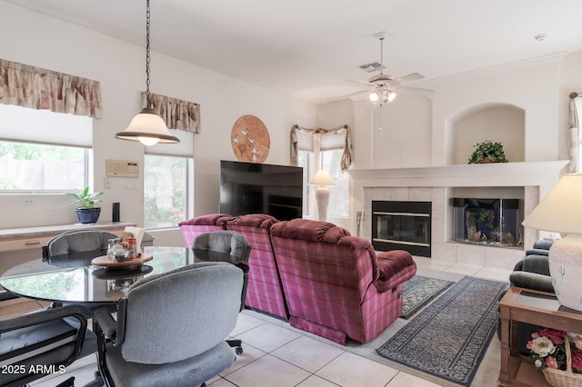 living area featuring light tile patterned flooring, ceiling fan, and a tiled fireplace