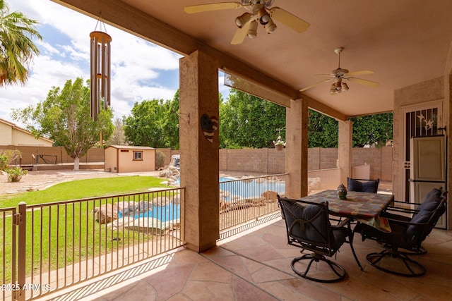 view of patio / terrace featuring a ceiling fan, outdoor dining area, an outdoor structure, and a storage unit