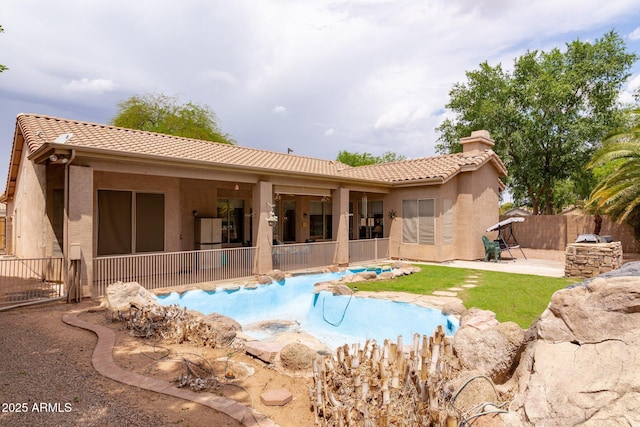 rear view of house with a tile roof, a patio area, a fenced backyard, and stucco siding