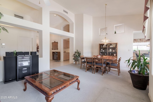 living area with a towering ceiling and light colored carpet