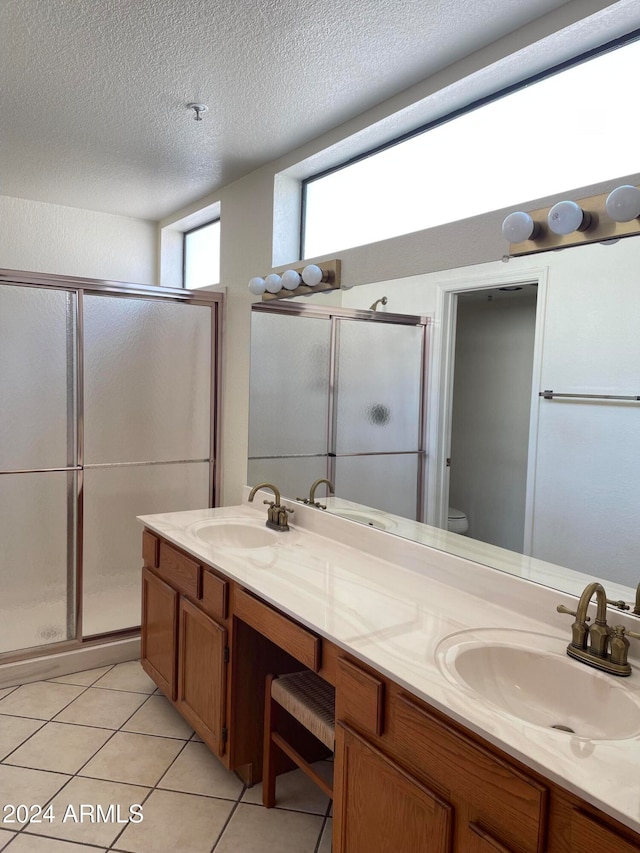 bathroom with vanity, a textured ceiling, toilet, and a shower with shower door