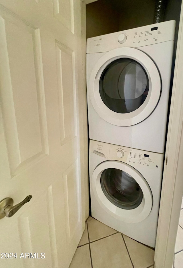 laundry room featuring stacked washer and clothes dryer and light tile patterned flooring