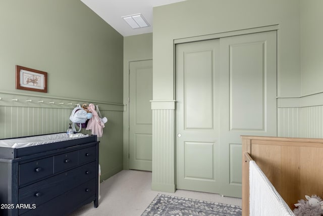 bedroom with a closet, visible vents, a wainscoted wall, and a decorative wall