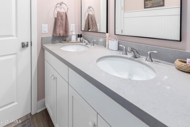 full bathroom with double vanity, a sink, and wood finished floors