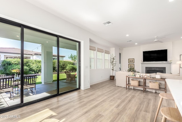living area with visible vents, a fireplace, light wood-type flooring, baseboards, and recessed lighting