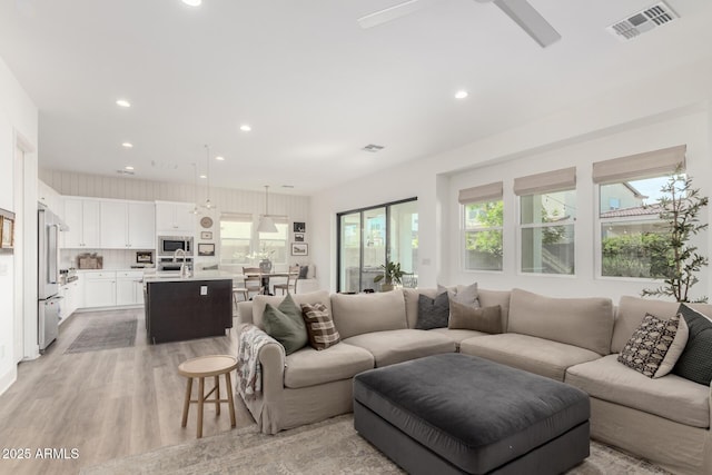 living room featuring ceiling fan, recessed lighting, light wood-style flooring, and visible vents