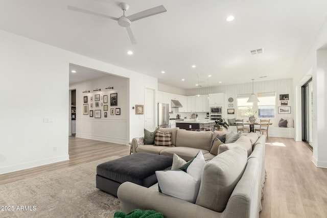 living area with visible vents, baseboards, ceiling fan, recessed lighting, and light wood finished floors