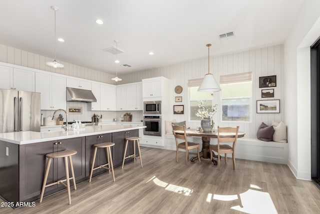 kitchen with visible vents, a sink, light countertops, under cabinet range hood, and stainless steel appliances