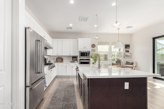 kitchen with visible vents, light countertops, white cabinets, light wood-style flooring, and stainless steel appliances