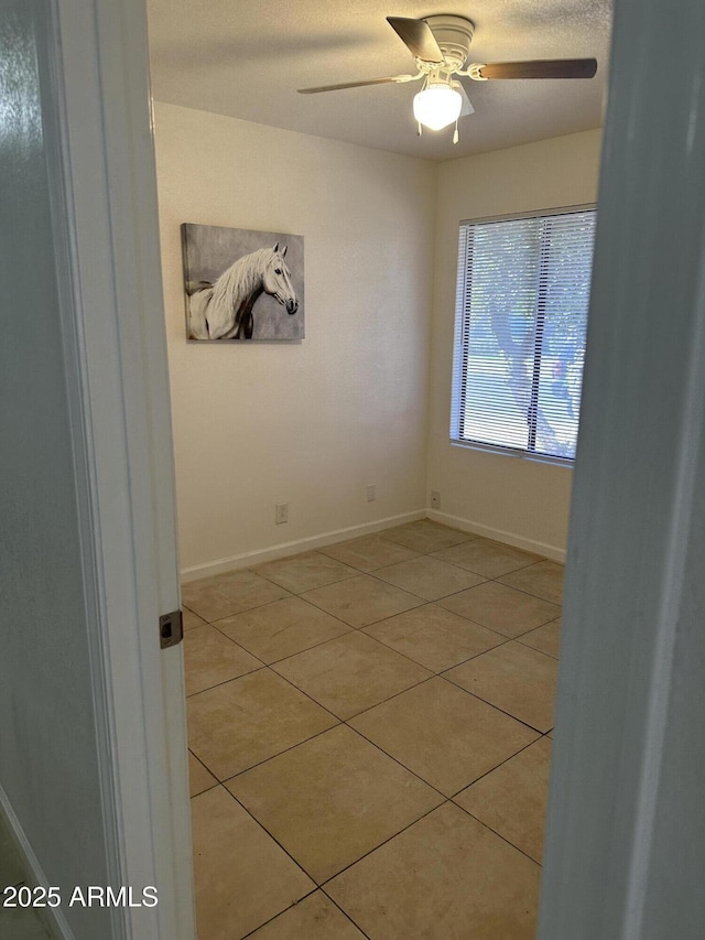 spare room with light tile patterned flooring and ceiling fan