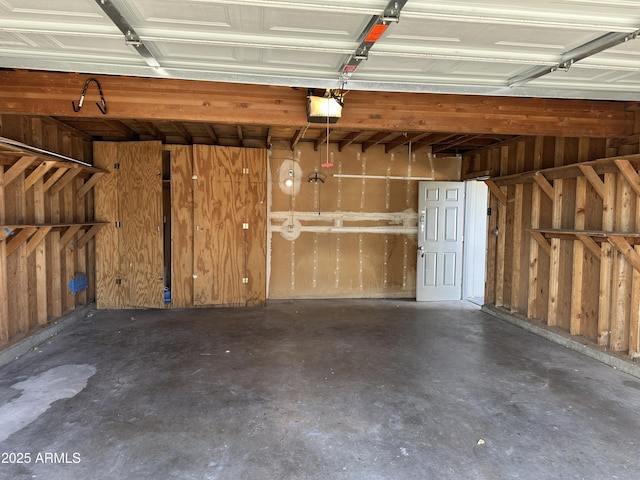 garage featuring a garage door opener and wooden walls