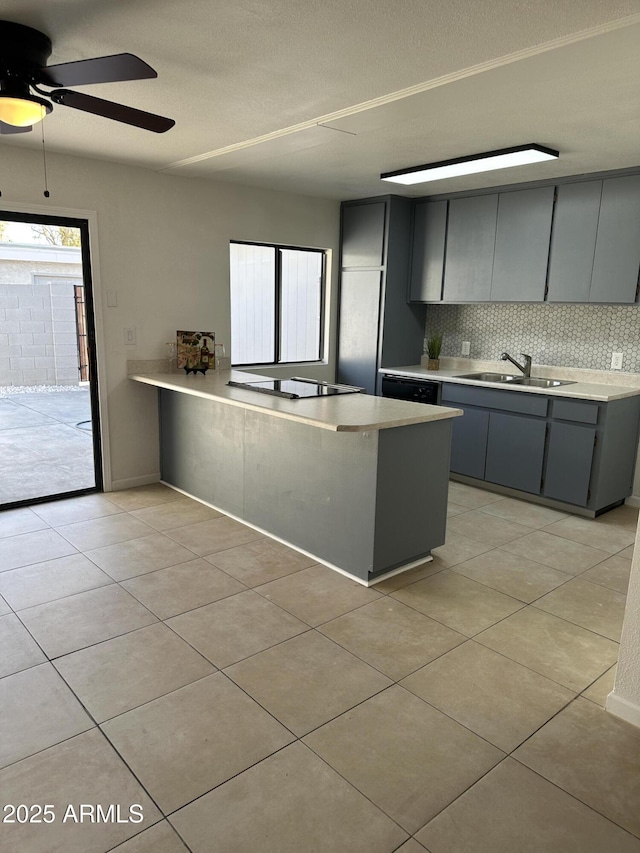 kitchen featuring sink, light tile patterned flooring, kitchen peninsula, decorative backsplash, and black appliances