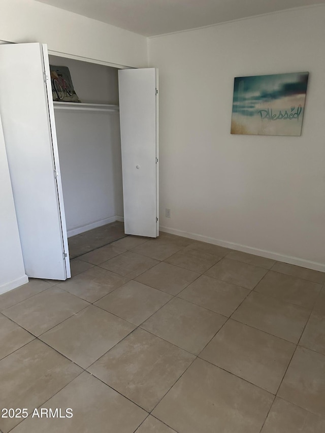 unfurnished bedroom with light tile patterned flooring, a closet, and white fridge