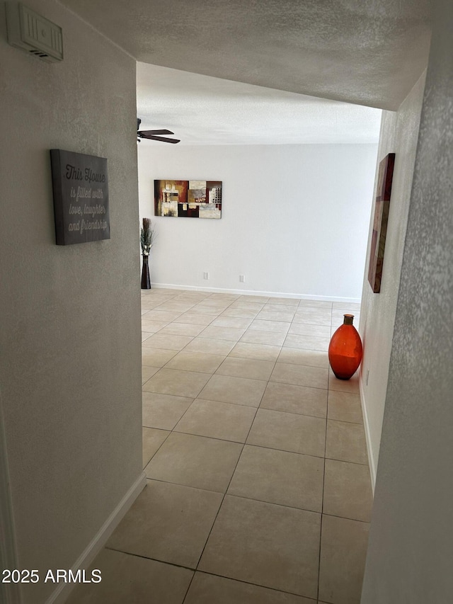 hallway with a textured ceiling and light tile patterned floors