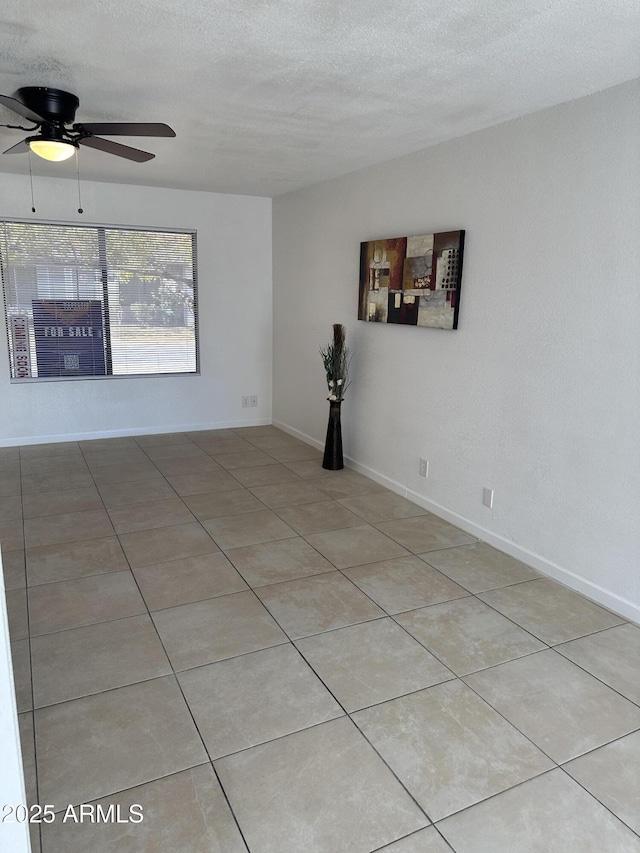 tiled empty room with ceiling fan and a textured ceiling