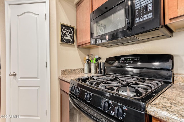 kitchen with black appliances, brown cabinetry, and light stone countertops