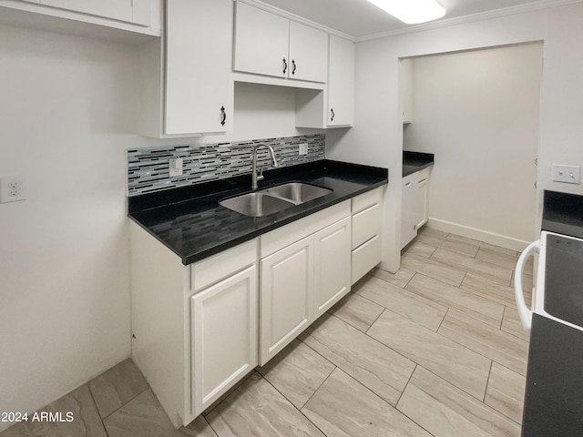 kitchen with crown molding, sink, tasteful backsplash, white cabinetry, and range