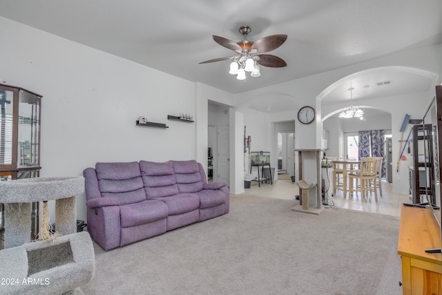 carpeted living room featuring ceiling fan with notable chandelier