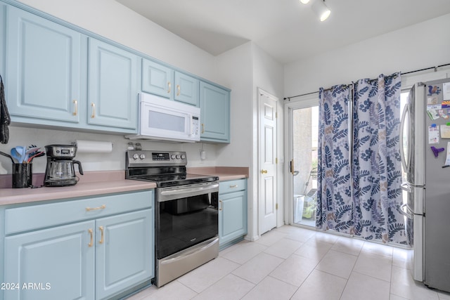 kitchen with appliances with stainless steel finishes, blue cabinetry, and light tile patterned floors