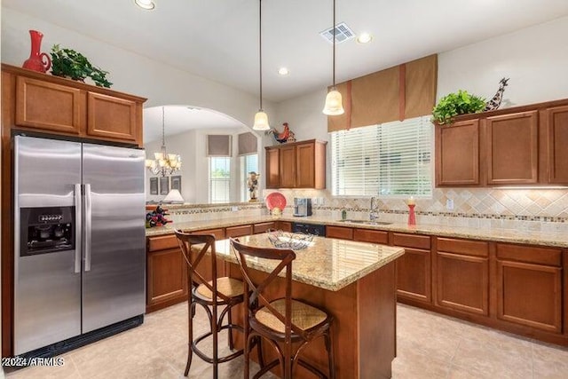 kitchen featuring tasteful backsplash, visible vents, brown cabinetry, stainless steel refrigerator with ice dispenser, and a sink