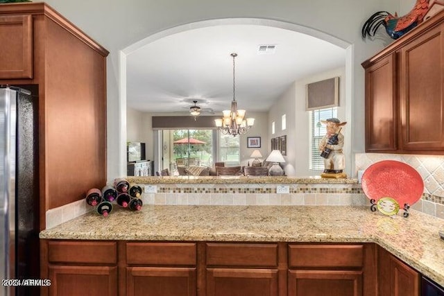 kitchen featuring visible vents, light stone counters, tasteful backsplash, and freestanding refrigerator