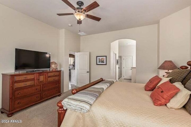 bedroom featuring a ceiling fan, arched walkways, light carpet, and ensuite bath