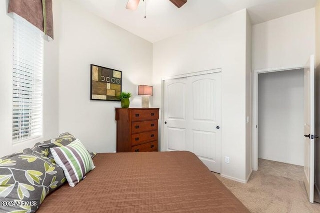 carpeted bedroom with ceiling fan and a closet