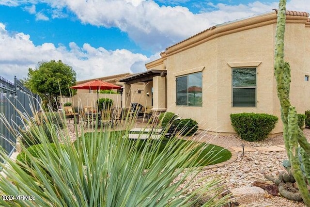 exterior space with a patio area, fence, and stucco siding