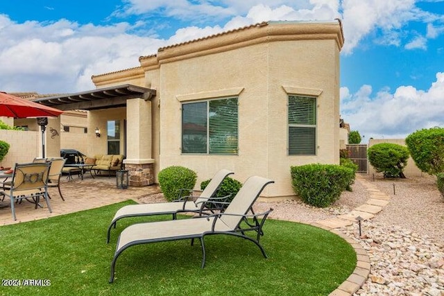 rear view of property featuring a yard, stucco siding, a patio area, fence, and a wall mounted air conditioner