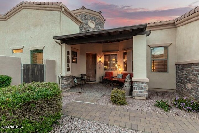 view of exterior entry featuring stone siding, a tiled roof, and stucco siding