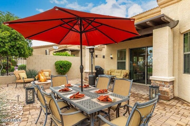 view of patio with a fire pit, fence, and outdoor dining space