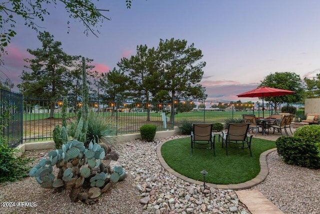 yard at dusk featuring a patio area and fence