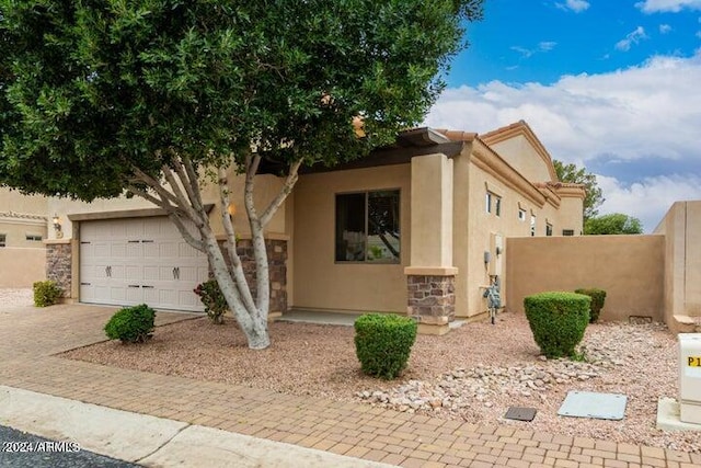 view of front of property featuring a garage, fence, stone siding, driveway, and stucco siding