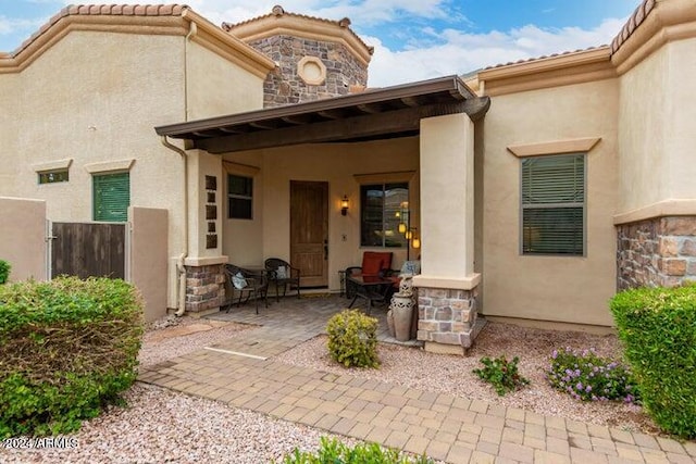 view of exterior entry with stone siding, a tiled roof, and stucco siding