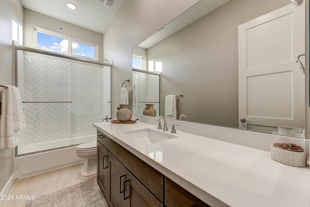 full bathroom with vanity, hardwood / wood-style flooring, toilet, and enclosed tub / shower combo