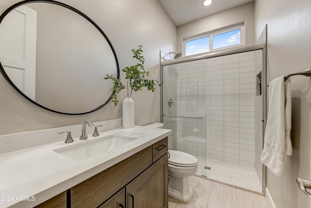 bathroom featuring a shower with door, vanity, and toilet