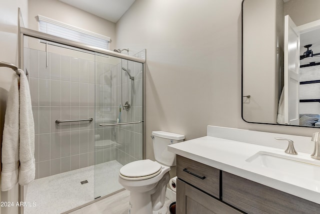 bathroom featuring hardwood / wood-style floors, vanity, toilet, and a shower with door