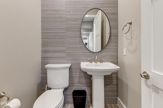 bathroom featuring sink, tile walls, and toilet