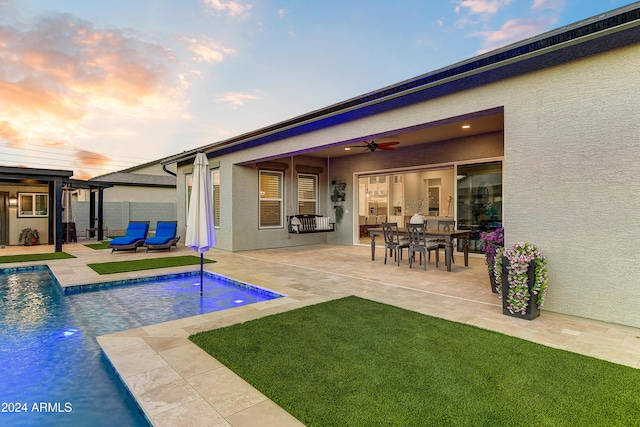 back house at dusk with ceiling fan and a patio area