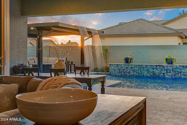 pool at dusk with a patio and pool water feature