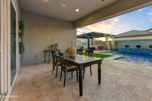 patio terrace at dusk featuring a fenced in pool, outdoor lounge area, and pool water feature