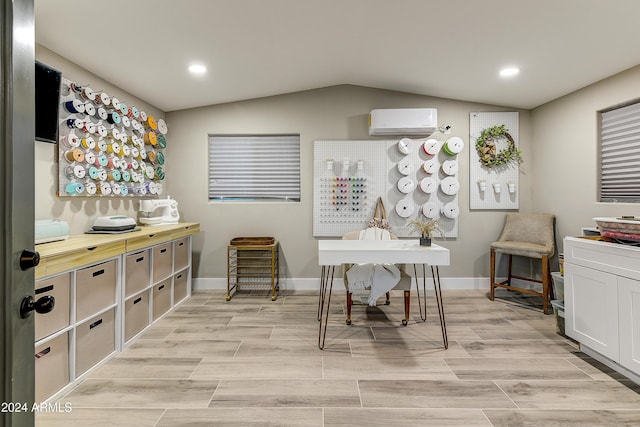 interior space with white cabinets, light wood-type flooring, a wall unit AC, and vaulted ceiling